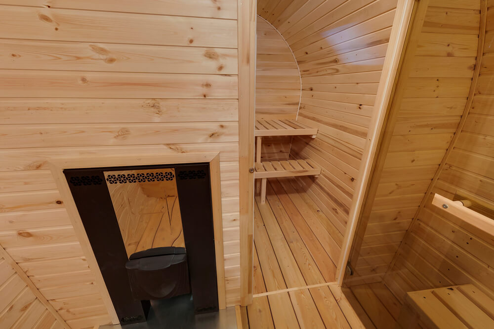 Ein Saunafass mit Vorraum steht wahlweise mit einem Holzofen oder Elektroofen zur Verfügung